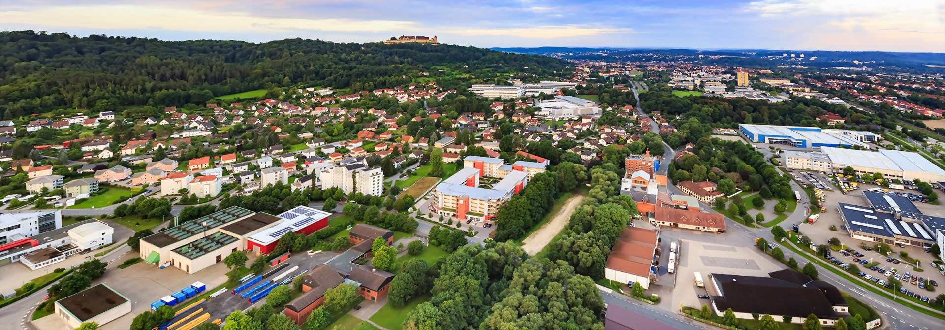 Luftaufnahme von Coburg zeigt eine malerische Stadtlandschaft mit Gebäuden, Straßen und üppigen Wäldern im Hintergrund.