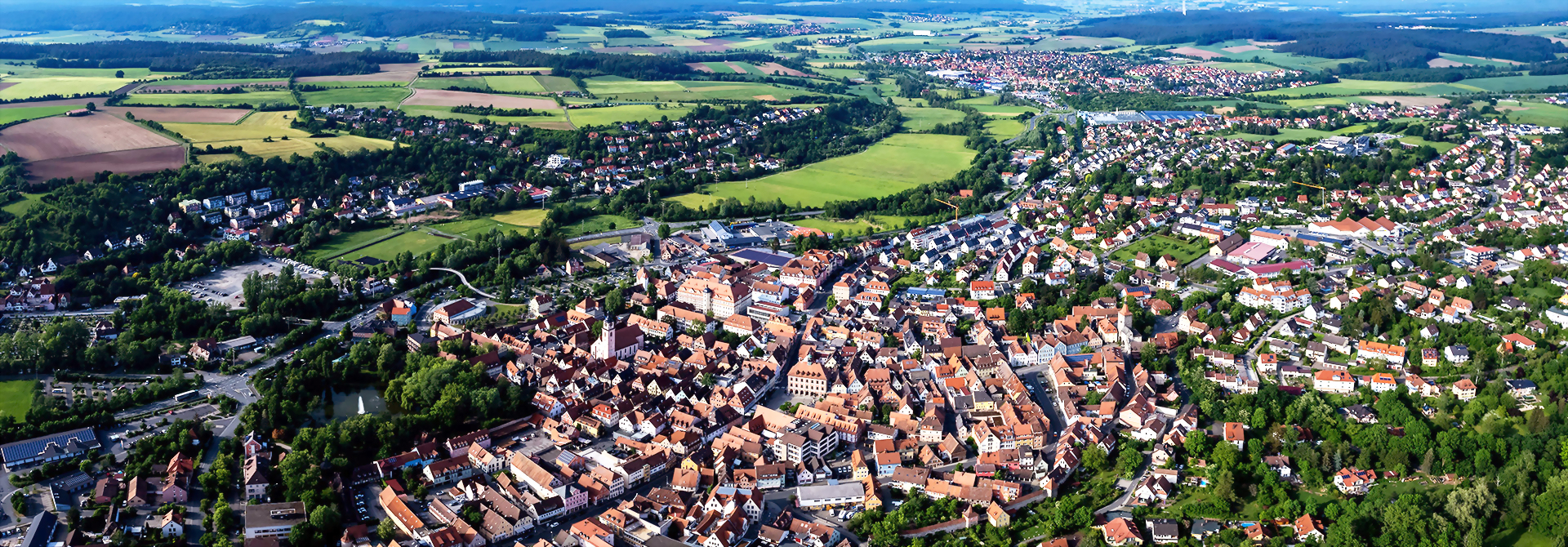Neustadt an der Aisch, aus der Luft: eine malerische Stadt mit historischen Gebäuden und viel Grün.