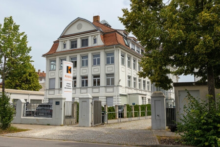 Die Adolph-Kolping-Berufsschule in Bamberg, ein großes weißes Gebäude mit einem Tor davor.  