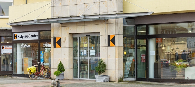 Eingang zum Kolping-Center mit Glasfront und zwei großen Kolping-Logos jeweils links und rechts vom Eingang an der Fassade.