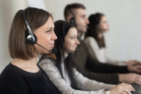 Callcenter-Mitarbeiter arbeiten zusammen, während sie Anrufe entgegennehmen und Informationen austauschen.  