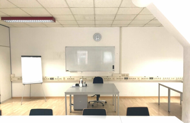 Seminarraum R 2.1 mit einem Whiteboard und Stühlen, bereit für Schulungen oder Besprechungen.