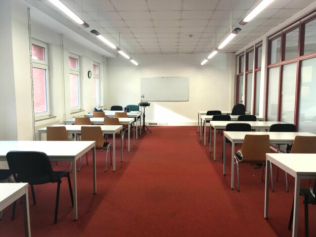 Seminarraum L 2.2 mit ordentlich angeordneten Tischen und Stühlen für den Unterricht.