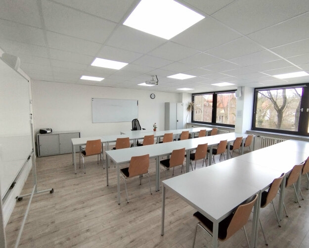 Schulungsraum 1 im ersten Obergeschoss, ausgestattet mit Tischen und Stühlen für den Unterricht.