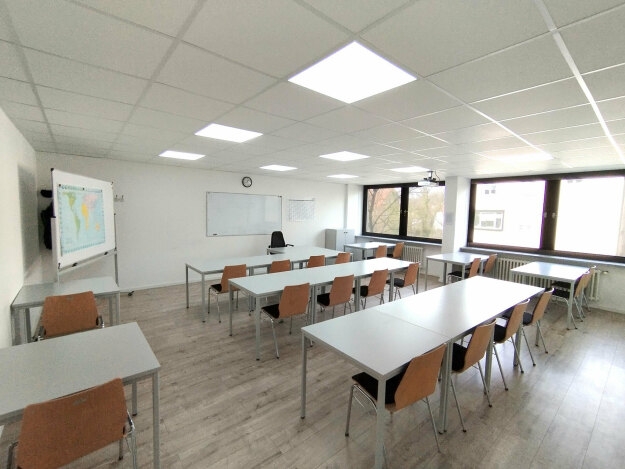 Schulungsraum 2 im ersten Obergeschoss, ausgestattet mit mehreren Tischen und Stühlen für den Unterricht.